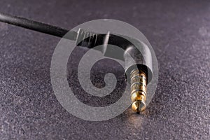 An image of a golden plated 3.5mm jack on a black background, showcasing the marriage of modern technology and aesthetic