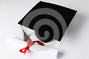 Image of graduation hat and diploma on white surface