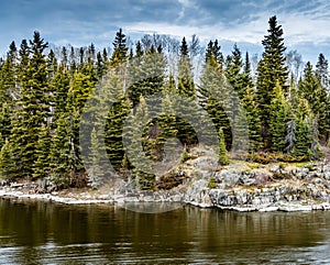 Image of the Grass river in northern Manitoba Canada, showing tall spruce trees and granite rock of the boreal forest.
