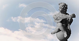 Image of gray sculpture of cupid over blue sky and clouds, copy space