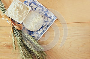 Image of greek cheese , bulgarian cheese and milk on wooden table over vintage rustic background. Symbols of jewish holiday -