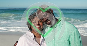 Image of green hearts over african american senior couple on the beach