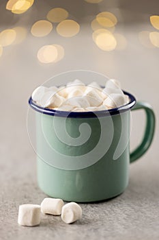 Image of green mug with christmas marshmallows with copy space and fairy lights in background