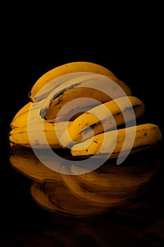 A hand of bananas on a wooden table and dark background