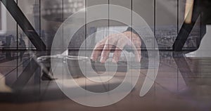 Image of hand of caucasian man using computer over cityscape