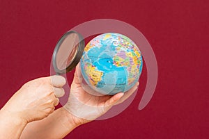 Image of a hand holding a magnifying glass over an world globe