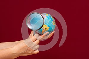 Image of a hand holding a magnifying glass over an world globe