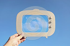 image of hand holding tv frame in front of sky with cloud. capture the moment or minimal concept.