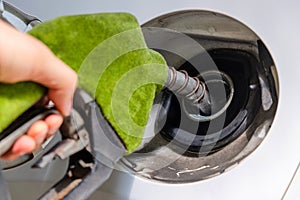 image of hand refilling a car with fuel at a gas station