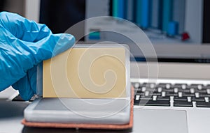 Image of hands in medical gloves on the background of a laptop. The woman holds a plastic bank card and enters the number on the