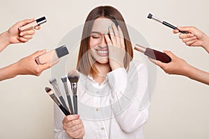 Image of the hands of several beauticians holding their respective equipment giving makeover to beautiful smiling woman with