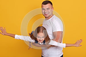 Image of handsome happy man teaching sweet lovely daughter to fly like plane, having fun together, spend time playing, isolated