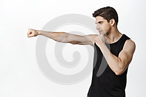 Image of handsome strong male athlete, sportsman wrestle, extending clenched fist for punch, workout in gym, fighting photo