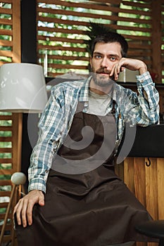 Image of handsome waiter boy sitting at the bar while working in cafe or coffeehouse outdoor