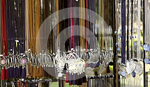 The image of hanging women`s jewelry on colored laces in the store. Fashionable jewelry on the neck for women.