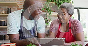 Image of happy african american couple using tablet over lightbulbs