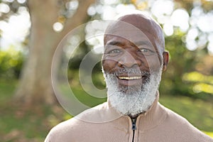 Image of happy african american man smiling at camera in garden