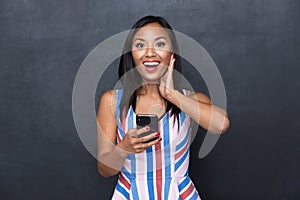 Image of happy asian woman 30s using black mobile phone standing isolated