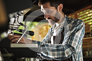 Image of happy barista man making coffee while working in cafe or coffeehouse outdoor