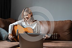 Image of happy beautiful woman playing guitar and composing song