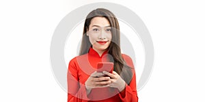 Image of happy beautiful woman in red vietnamese tranditional dress, holding smartphone