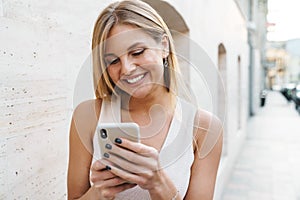 Image of happy blonde woman smiling and using mobile phone