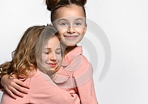 Image of a happy cheerful girl hugging her little sister or friend on a white background.