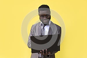 Image of happy excited young african man isolated over yellow background using laptop computer