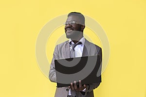 Image of happy excited young african man isolated over yellow background using laptop computer