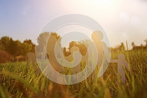 Image of happy family concept. paper cut people holding hands together in green grass during sunset.