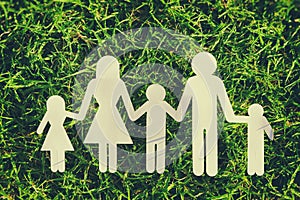 Image of happy family concept. paper cut people holding hands together over green grass.