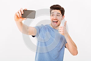 Image of happy guy in studio smiling and showing thumb up while