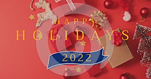 Image of happy holidays christmas text over decorations on red background