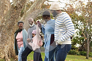 Image of happy multi generation african american family having fun outdoors in autumn