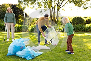 Image of happy multi generation caucasian family collecting waste in garden