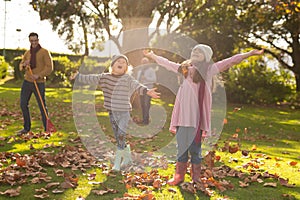 Image of happy multi generation caucasian family having fun with leaves in autumn garden