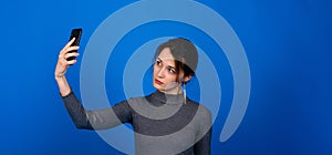 Image of a happy surprised shocked young pretty woman posing isolated over blue background using mobile phone