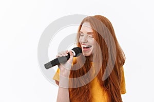 Image of happy woman with curly hair singing while holding microphone isolated over white background