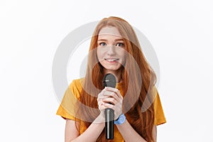 Image of happy woman with curly hair singing while holding microphone isolated over white background