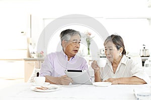 Japanese senior couple, enjoying coffee in the kitchen at home,