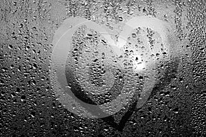 Image of a heart and a question mark on a wet misted window. Emo