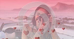 Image of hearts floating over happy biracial woman taking photo at cabriolet