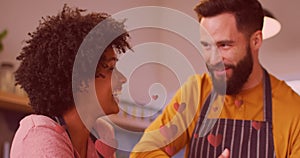 Image of hearts ove diverse couple preparing meal in kitchen