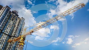 Image of high building crane on construction site against blue sky and skyscrapers