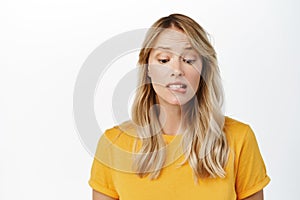 Image of hopeful cute blond girl yearning, want smth, look with desire and hope, stands in yellow t-shirt over white