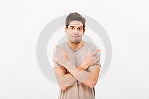 Image of indecisive man wearing beige t-shirt gesturing fingers