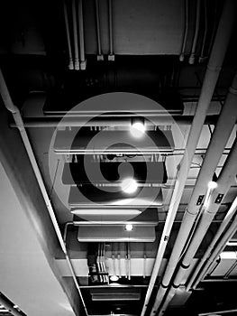 Monochrome indoor ceiling showing pipeline, lights, and electric lines