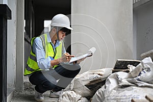Image of inspector or engineer writing on clipboard, checking building material at construction site