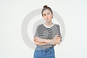 Image of intrigued young woman, thinking, pucker lips with thoughtful face, cross arms on chest, standing over white