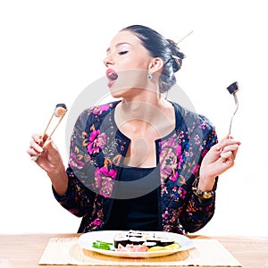 Image of isolated on white background beautiful seductive brunette woman eating sushi with chopsticks and fork